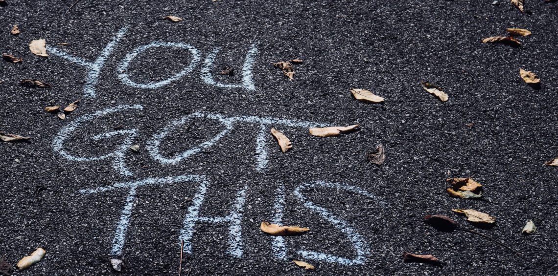 Sidewalk chalk that says "You Got This" on asphalt.