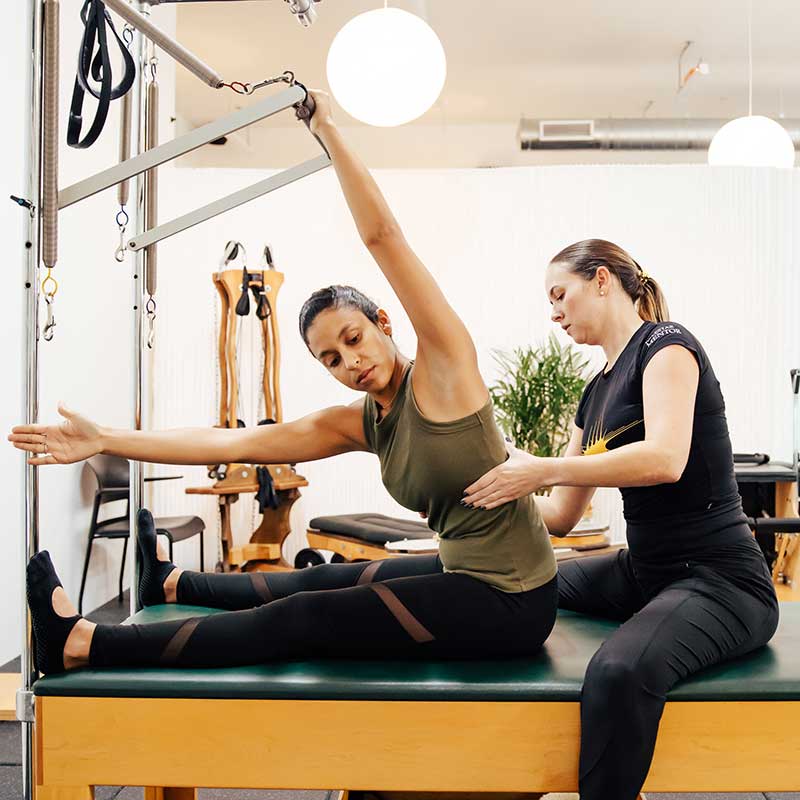 Host Pilates Courses in your Studio. Instructor teaching a student on the cadillac.
